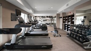 Un gimnasio con cintas de correr, mancuernas y equipamiento de ejercicio.