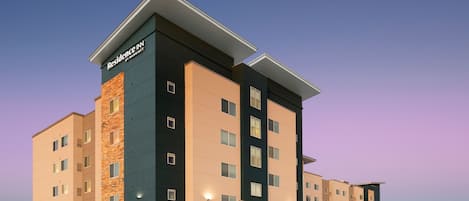 A multi-story hotel with a flat roof, a sign reading "Residence Inn by Marriott," and a flagpole with an American flag.