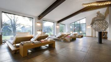 A spacious room with large windows, a wooden bench with books, and a unique decorative light fixture.