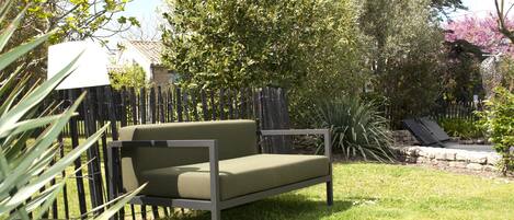A garden with a green sofa, a wooden fence, and various plants.