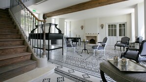 Un saló espaiós amb un piano de cua, un paviment amb dibuixos i una escala amb baranes de fusta.