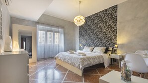 A modern bedroom with a large bed, a desk, and a chair. There is a patterned wall and a window with curtains. - B&B Zen Trastevere (Rome)
