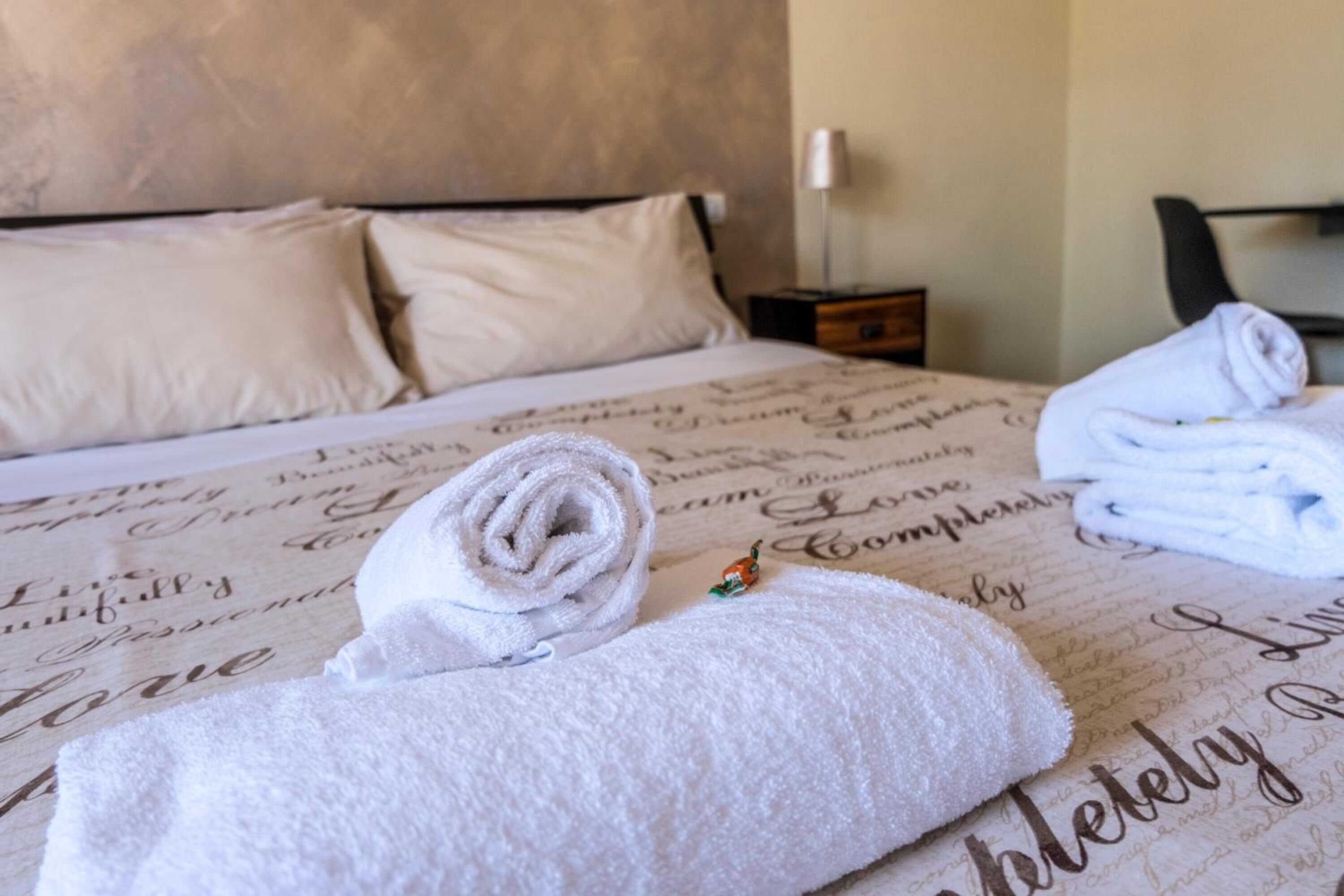 Ein ordentlich gemachteres Bett mit einer gemusterten Tagesdecke, einem gefalteten Handtuch und einem kleinen dekorativen Gegenstand.
