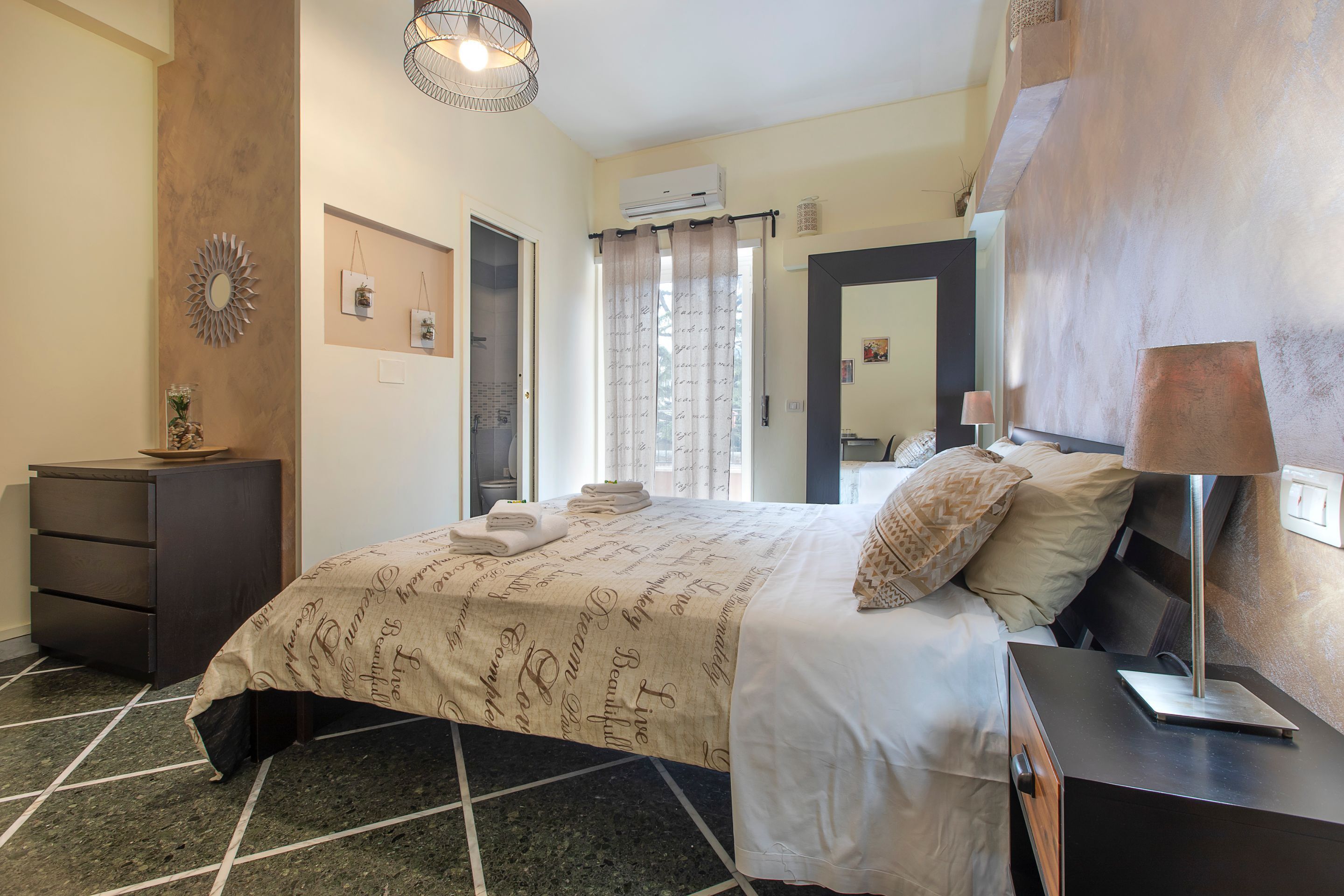 A bedroom with a bed, a dresser, a nightstand, and a mirror.