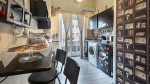 A compact kitchen with a dining area, a washing machine, and a wall with numbered storage boxes. - B&B Zen Trastevere (Rome)