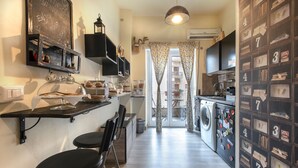 A compact kitchen with a bar area, a washing machine, and a wall with numbered storage boxes. - B&B Zen Trastevere (Rome)