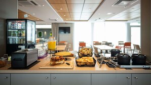 Un bufé de desayuno con diferentes alimentos, un refrigerador y una cafetera.
