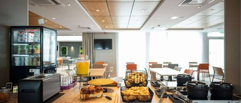 A breakfast buffet with various food items, a refrigerator, and a coffee machine.