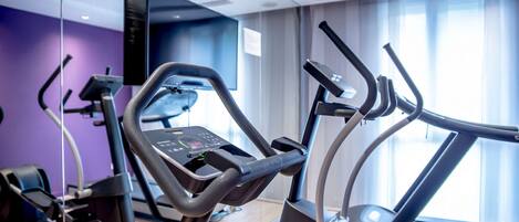 A modern gym with elliptical machines, a treadmill, and a stationary bike.