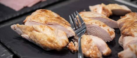 A close-up of sliced cooked chicken on a black plate.