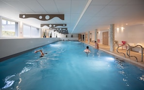 Relax by the serene indoor pool, surrounded by lush greenery and a modern ceiling design.