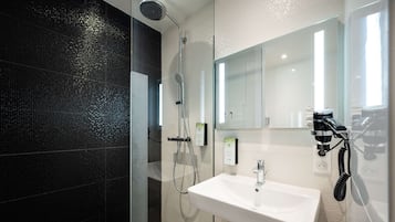 A modern bathroom with a glass-enclosed shower, a white sink, and a mirror.