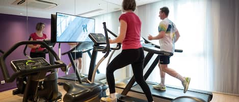 A gym with treadmills, a stationary bike, and a mirrored wall.