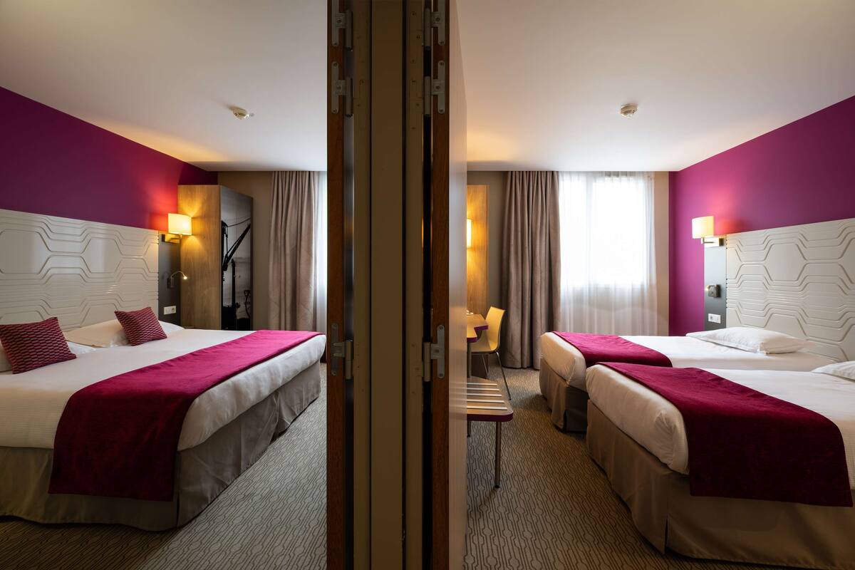 Habitación de hotel con dos camas, un escritorio y una silla.