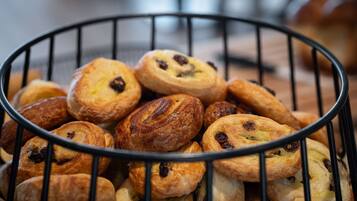 A basket of assorted pastries, including some with raisins and others with a golden-brown crust.