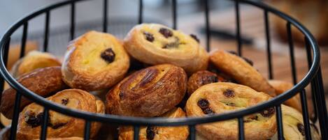 A basket of assorted pastries, including some with raisins and others with a golden-brown crust.