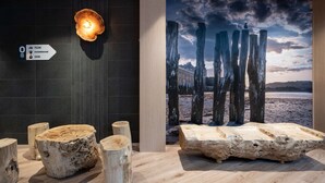 Un interior moderno con una pared oscura, suelo de madera y un cartel grande con una escena costera.