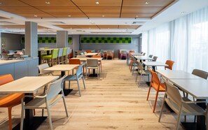 Enjoy meals in a stylish dining area with tables and chairs, surrounded by a clean, contemporary design.