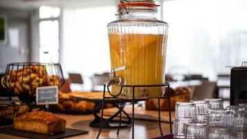A buffet setup with a large glass punch bowl, bread baskets, and a sign indicating the availability of coffee and tea.