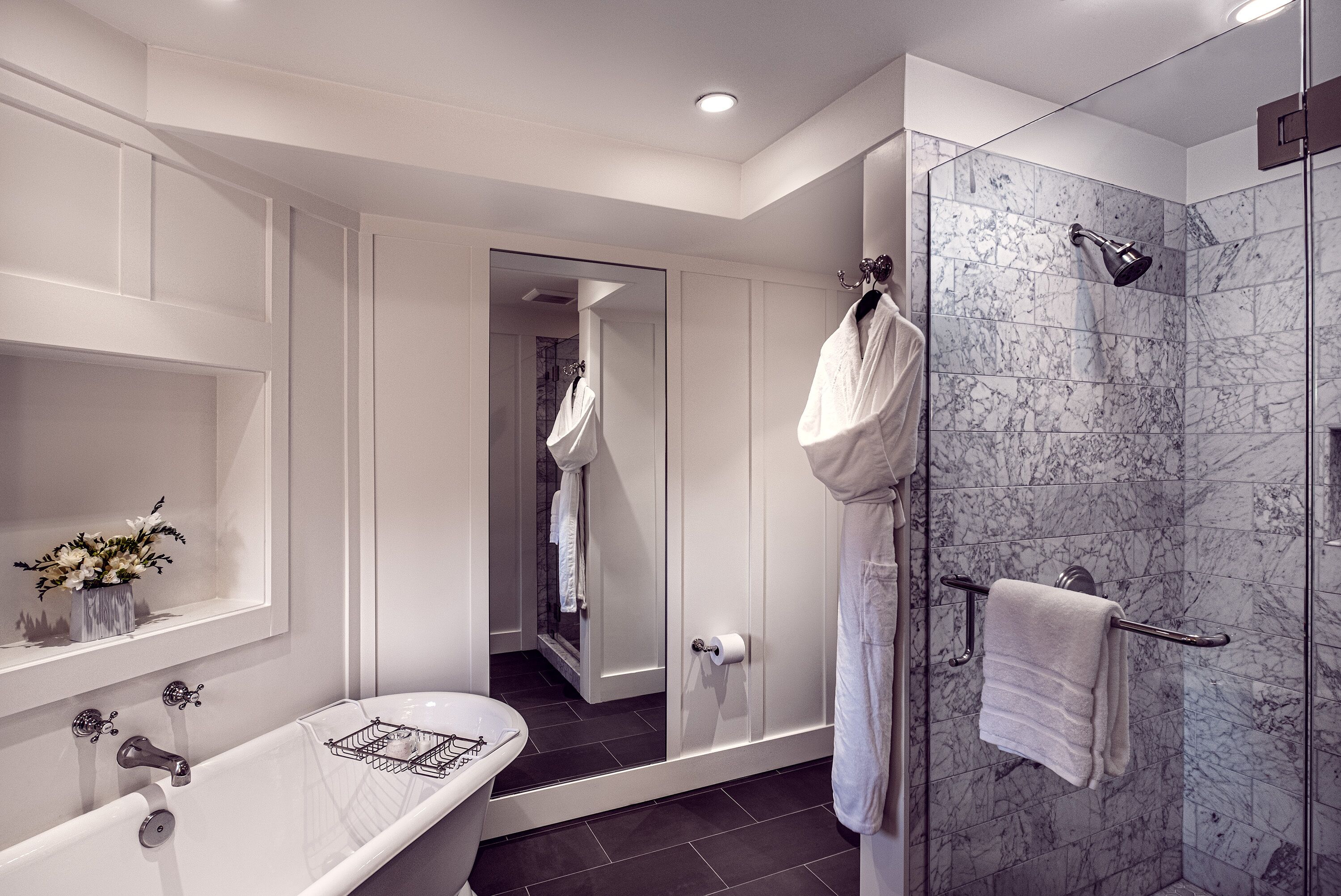 A modern bathroom with a bathtub, a glass-enclosed shower, and a vanity with a mirror.