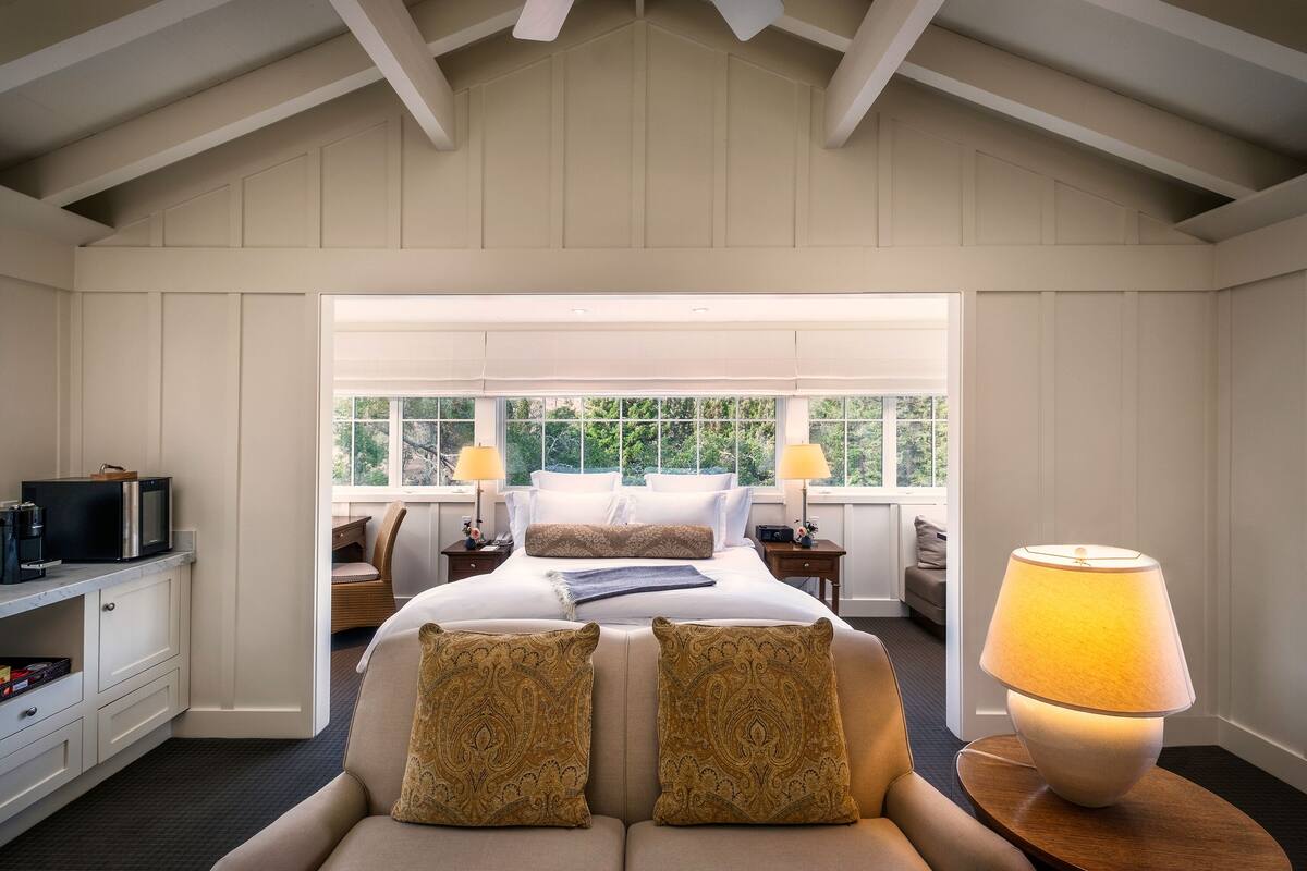 A bedroom with a bed, bedside tables, a TV, and a lamp.