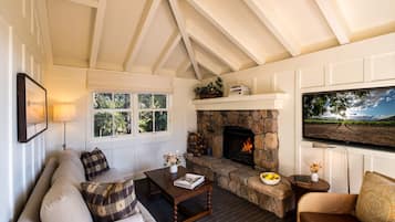 A cozy living room with a stone fireplace, a sofa, a coffee table, and a television mounted on the wall.