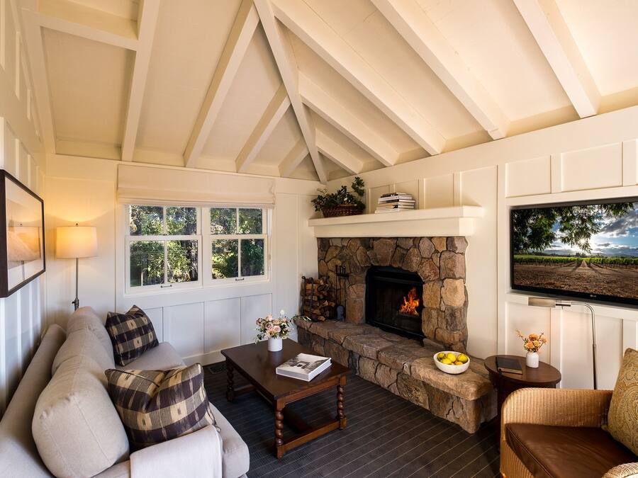 A cozy living room with a stone fireplace, a sofa, a coffee table, and a television mounted on the wall.