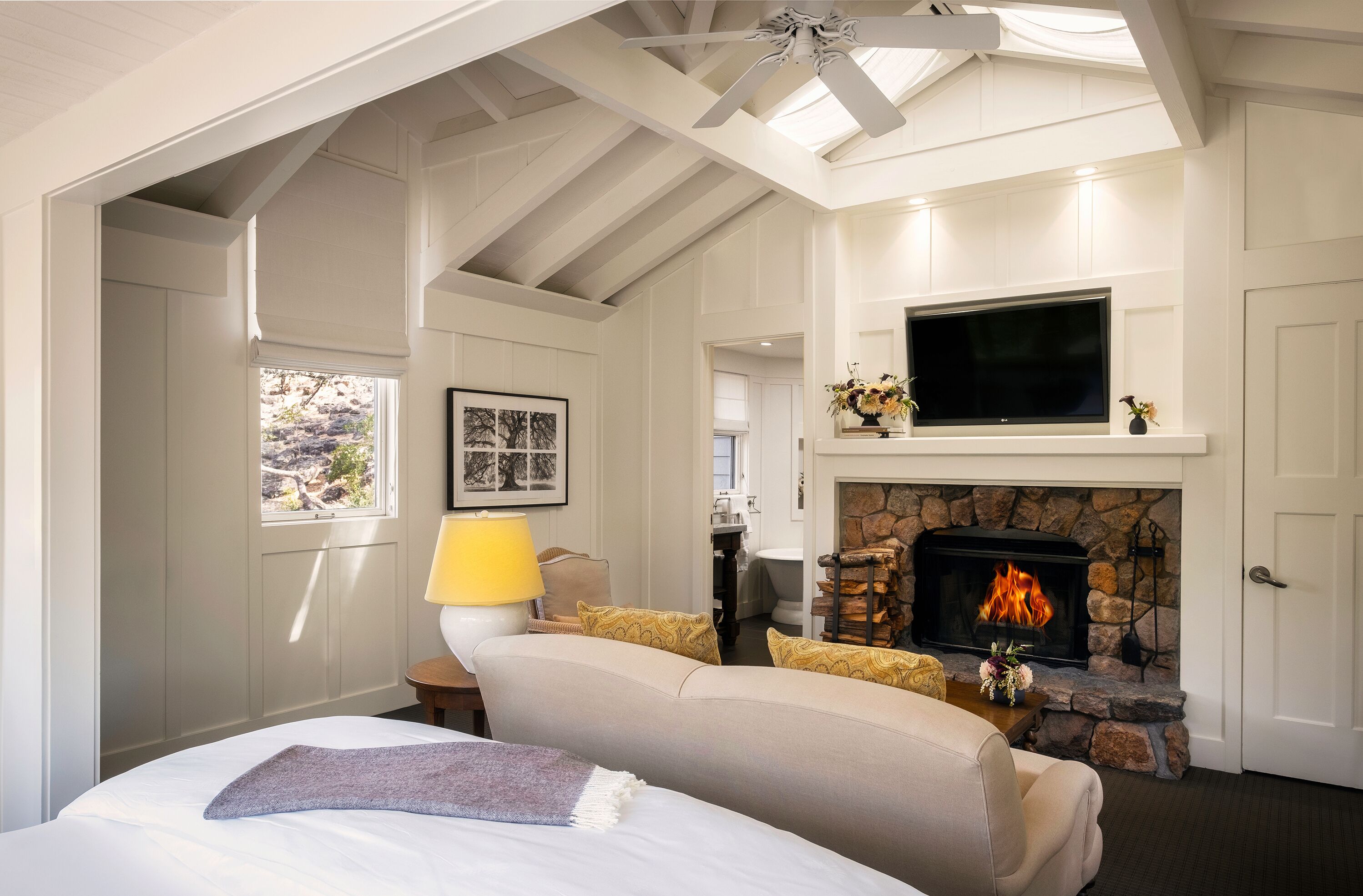 A cozy room with a fireplace, a bed, a TV, and a window with a view.