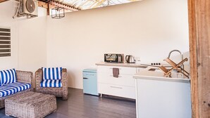 A rustic kitchen with a wooden ceiling, a small dining area with wicker furniture, and a kitchenette with a microwave and kettle. - Landhuis Daniel Hotel (Daniel)