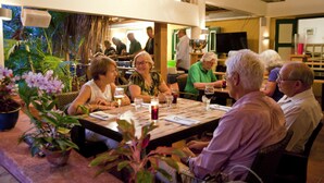 A group of people dining at an outdoor restaurant with a thatched roof and potted plants. - Landhuis Daniel Hotel (Daniel)