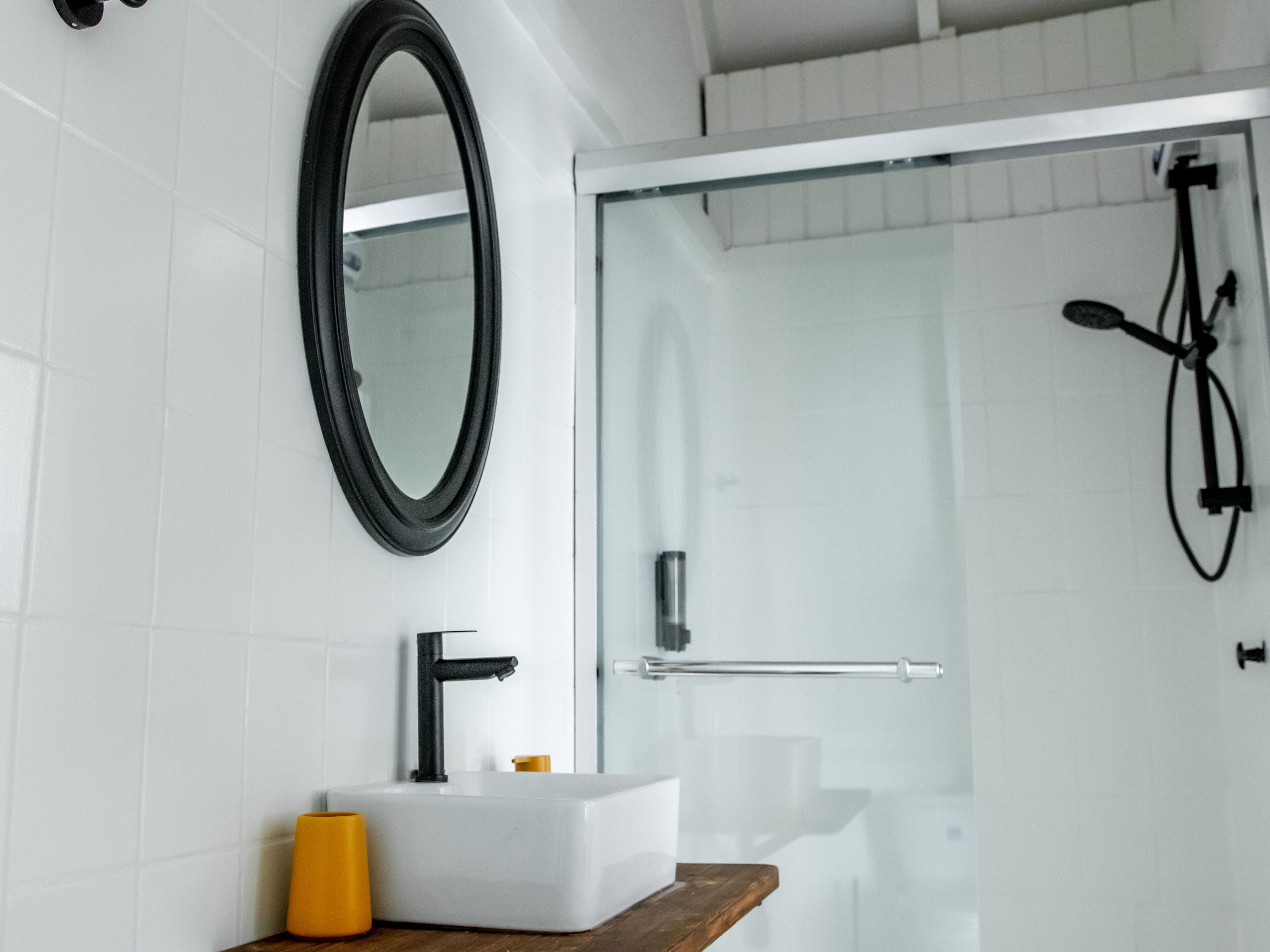 Une salle de bain moderne avec un lavabo blanc, un robinet noir et un miroir.
