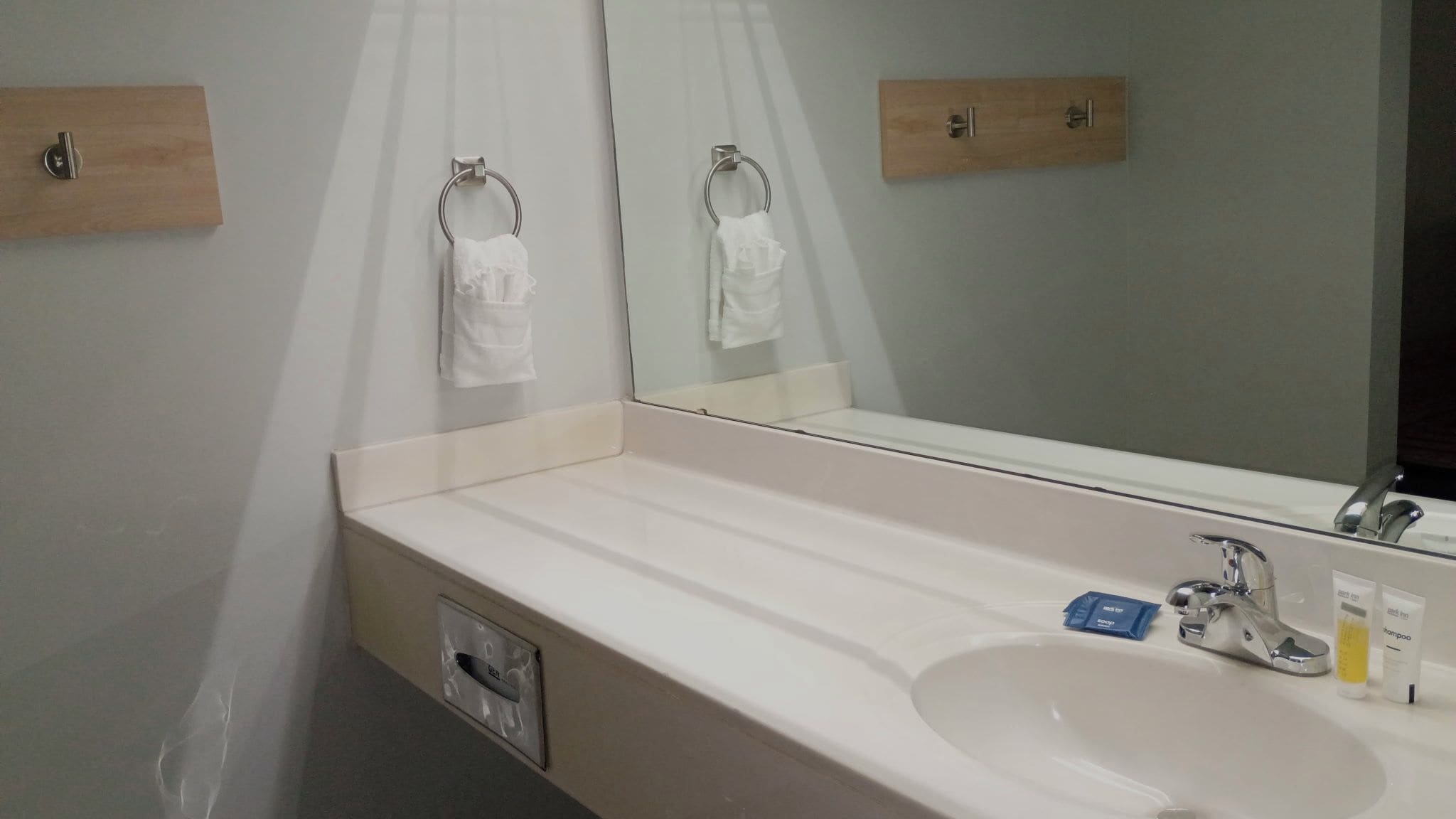 A hotel bathroom with a white sink, a mirror, and two towel racks.