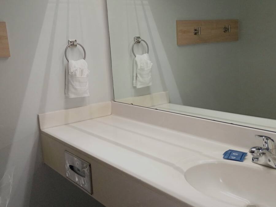 A hotel bathroom with a white sink, a mirror, and two towel racks.