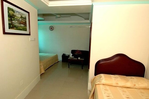 A room with a bed, a sofa, and a small table. There is a painting on the wall and a clock on the wall. - Grand Prince Hotel (Dhaka)