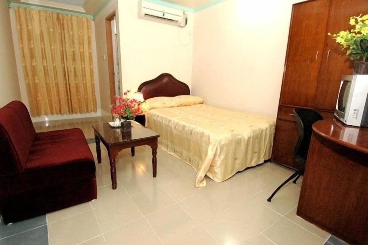 A hotel room with a bed, a desk, a chair, a TV, and a curtain.
