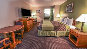 Een hotelkamer met een bed, een bureau, een stoel, een televisie en een badkamer die door een open deur zichtbaar is.