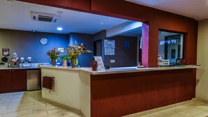 Een hotel receptie met een balie, een klok en een bordje dat een maximaal aantal van 20 personen aangeeft.