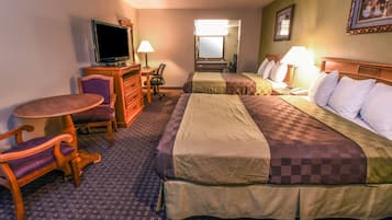 Habitación de hotel con cama, escritorio, silla, televisor y espejo.