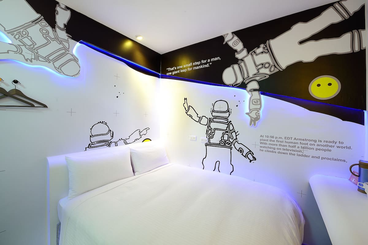 A room with a bed, a wall with astronaut illustrations, and a text about a space mission.
