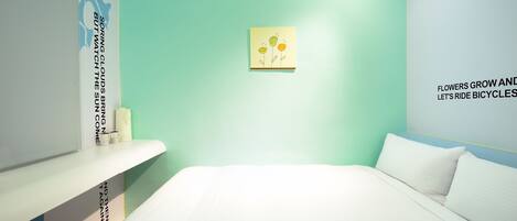 A bedroom with a bed, a nightstand, and a wall with a floral painting and motivational text.