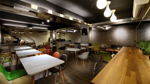 A modern restaurant interior with wooden tables, chairs, and a brick wall. - NL Concept Hotel (Kaohsiung)