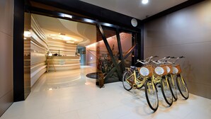 A modern interior with a staircase leading to a second floor, a reception area, and a row of bicycles with baskets. - NL Concept Hotel (Kaohsiung)