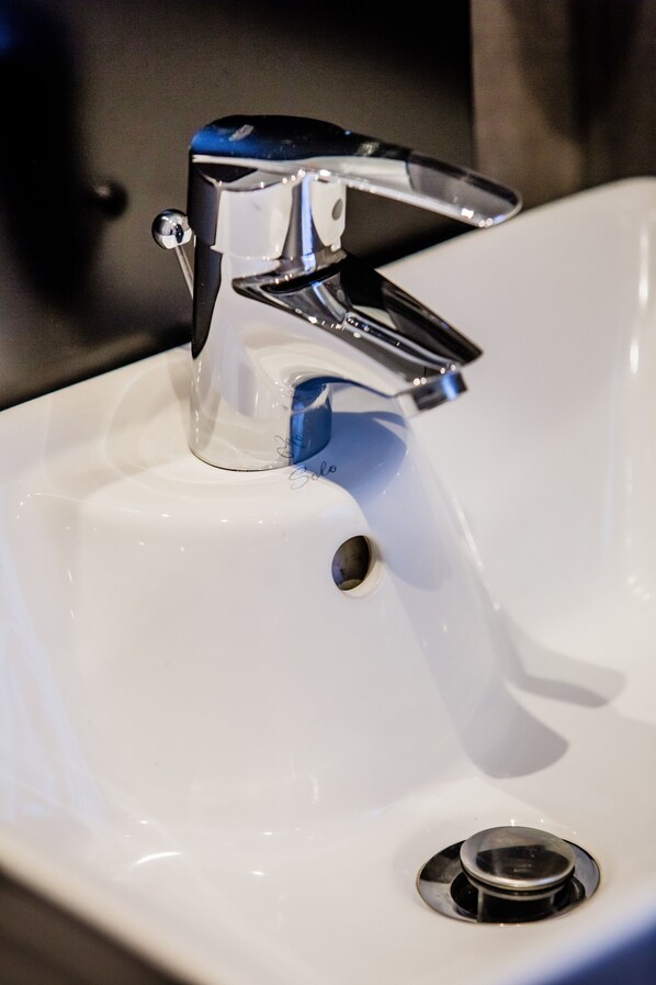 A white sink with a modern chrome faucet and a visible drain.