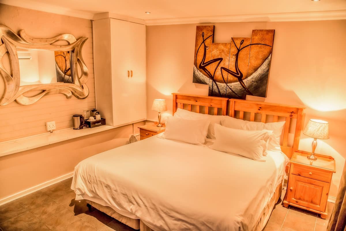 A neatly made bed with white linens, a wooden headboard, and two bedside tables with lamps.