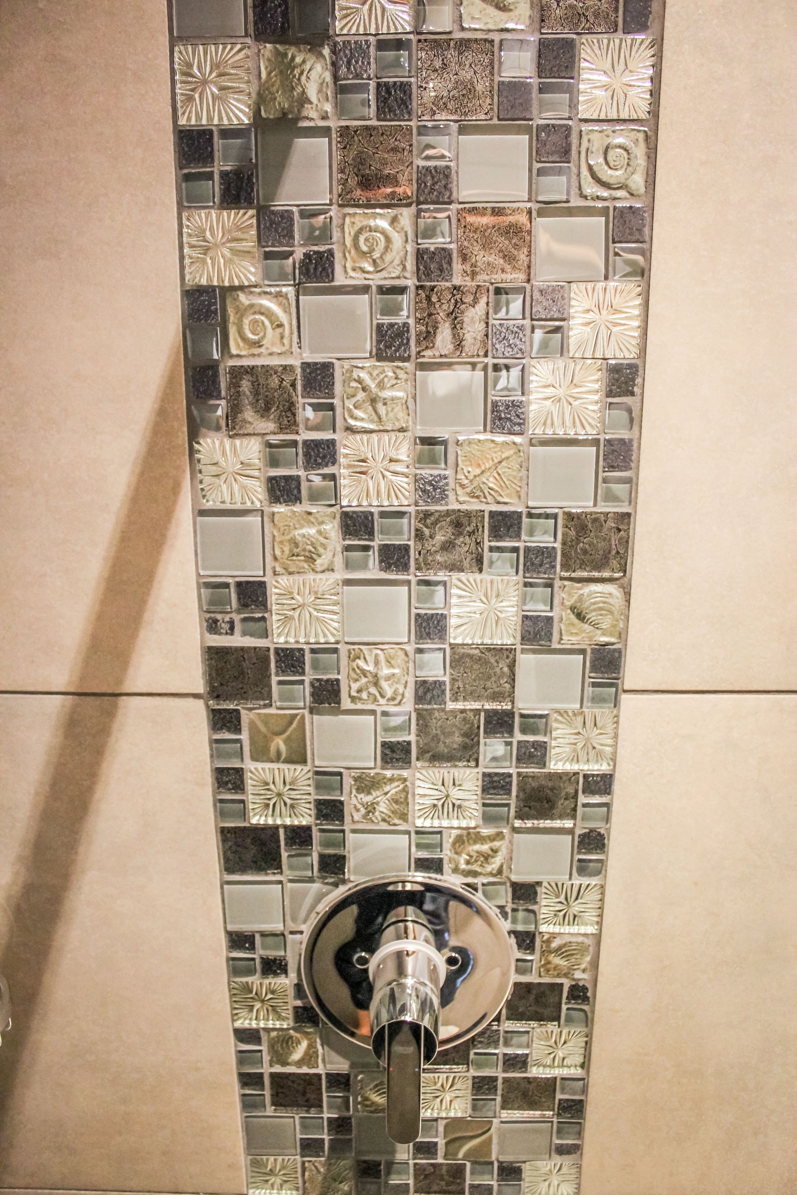 Un baño con un salpicadero de mosaicos y un grifo moderno.