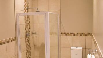 Een badkamer met een douche met glazen wand, een toilet en een handdoekrek.