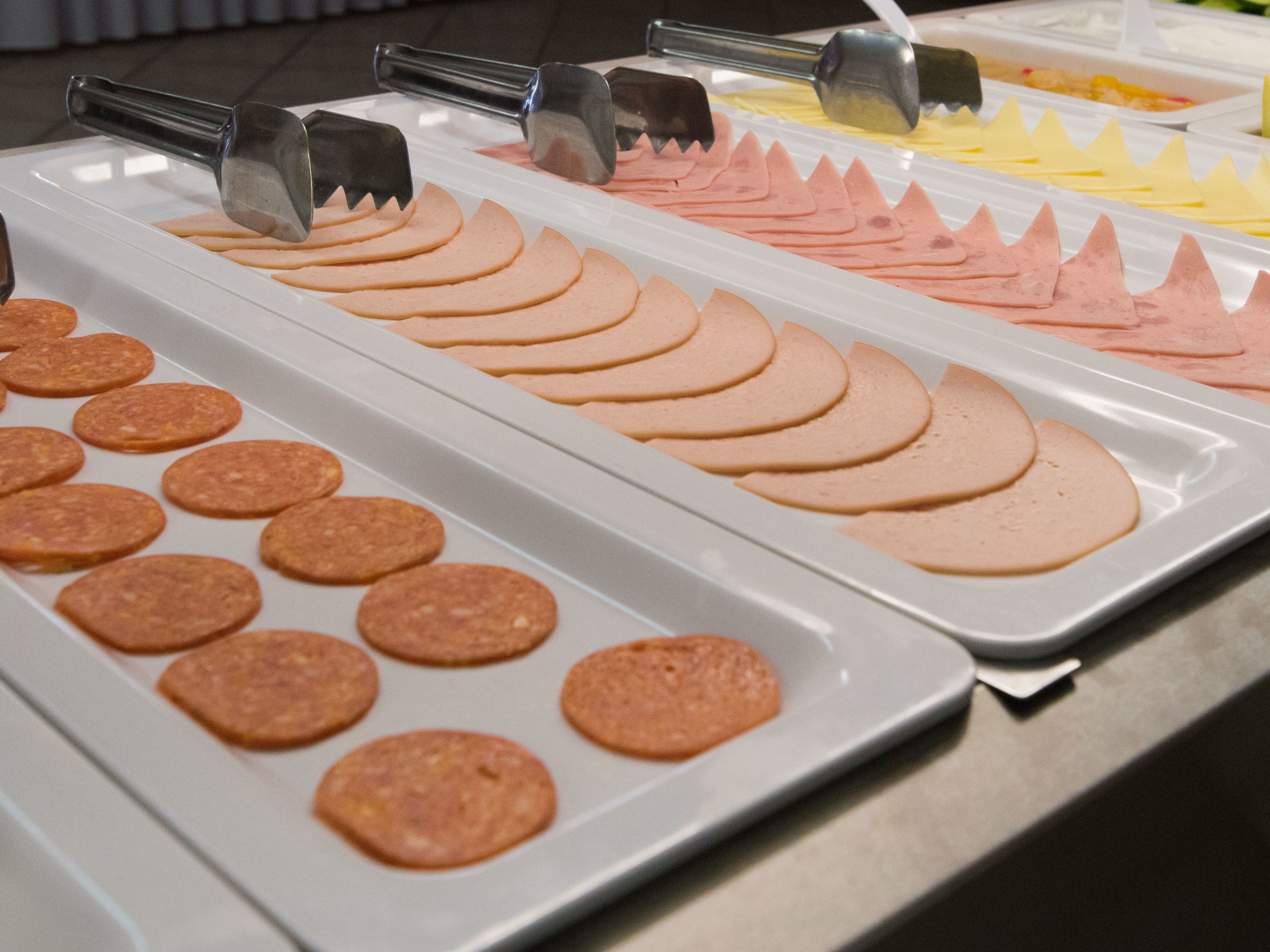 A buffet with various food items including sliced meats and cheeses.