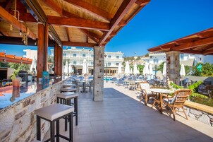 An outdoor bar area with stone walls, wooden beams, and outdoor seating.