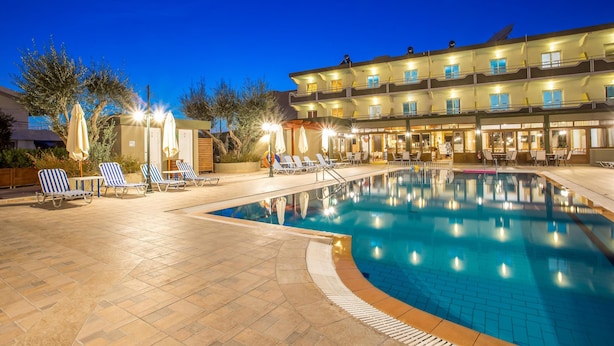 Un hotel con piscina, sillones de descanso y sombrillas.