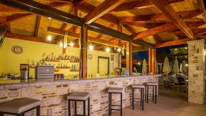 Una zona de bar con paredes de piedra, vigas de madera y taburetes.
